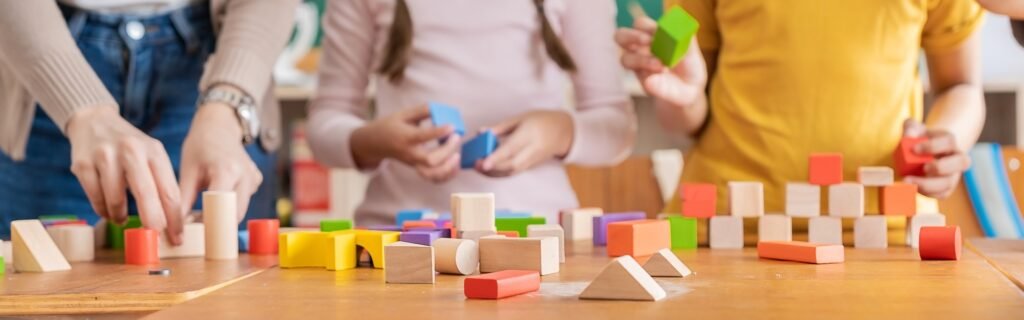 hands of little children playing blocks in classroom. Learning by playing education group